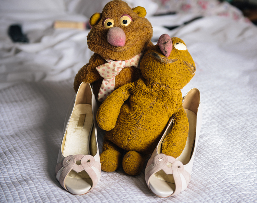 Barndomens mjukisdjur håller brudens bröllopsskor av vintage